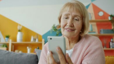 صورة توضيحية لسيدة مسنة تستخدم الهاتف في المنزل وليست إحدى ضحايا الاحتيال